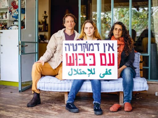Sofia Orr et ses parents, chez eux, à Pardes Hanna. Sofia s’apprête à refuser en août 2023 de faire le service militaire. Elle a la chance – le « privilège », dit-elle – de bénéficier du soutien de ses parents. Sur la pancarte, en hébreu : « Il n’y a pas de démocratie sous occupation », et en arabe (ligne du dessous) : « Assez avec l’occupation ». Photo : Haidi Motola pour La Déferlante