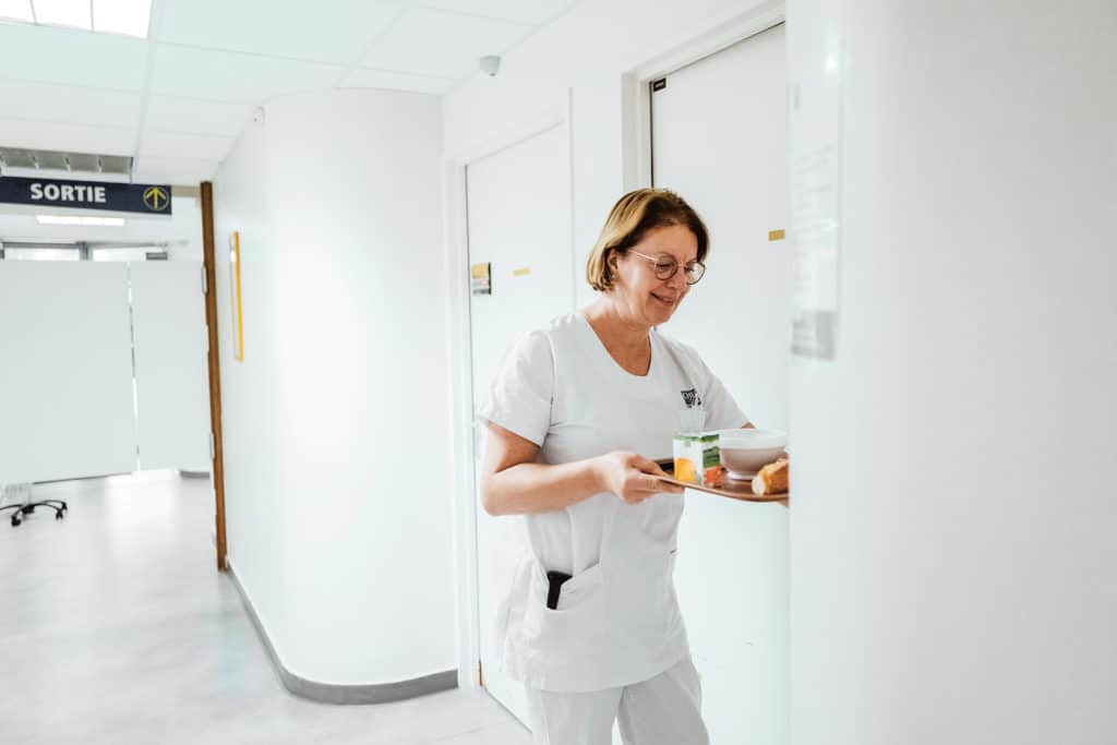Jeannine apporte un petit déjeuner dans la chambre d’une patiente, le « moment réconfortant », souligne l’aide-soignante.