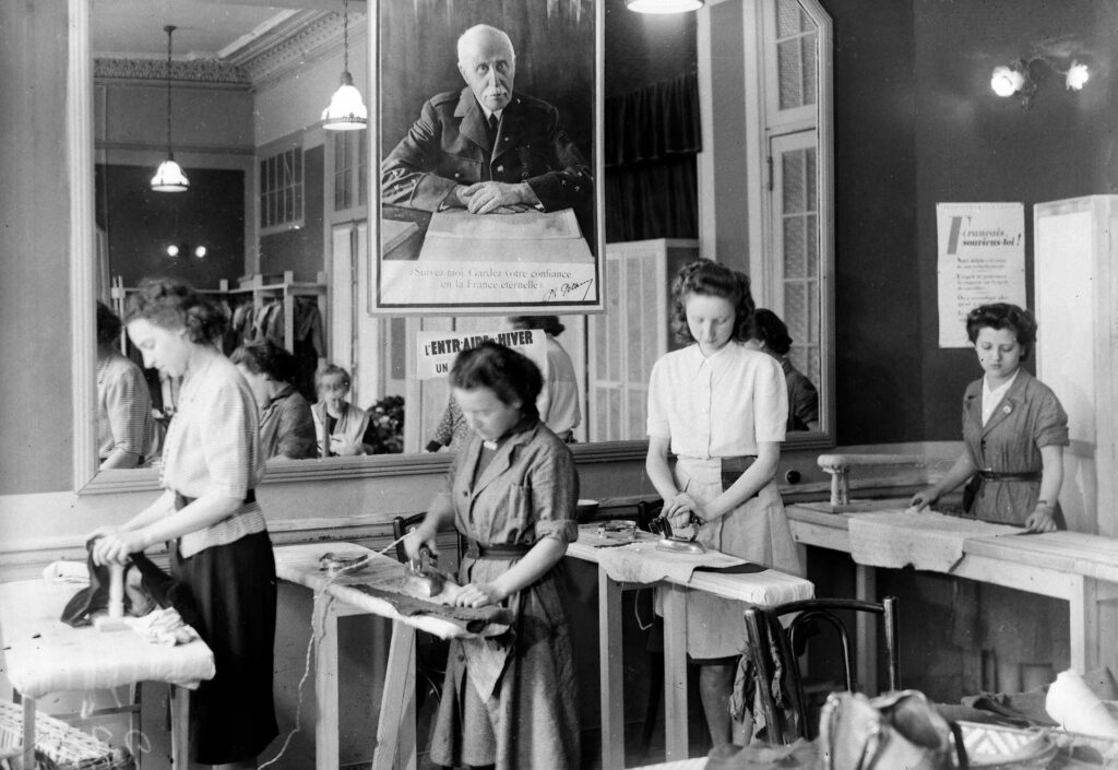 À Vichy, en 1942, sous une photographie du maréchal Pétain, des femmes prennent part à une séance de repassage organisé par le Secours national. KEYSTONE-FRANCE/GAMMA-RAPHO